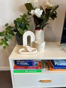 a shelf with books and a vase with flowers at Cosy getaway in the Heart of Braddon - Hosted by Canstay in Canberra +9 photos