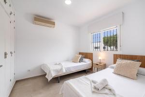 two beds in a white room with two windows at Villa Empul La Caracola in Chiclana de la Frontera +17 photos