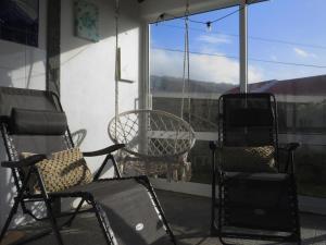 a porch with chairs and a table and a window at Mosteiros Coastal Haven in Mosteiros