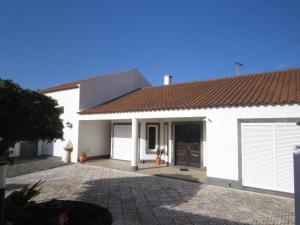 a white house with a brown roof and a driveway at Mosteiros Coastal Haven in Mosteiros