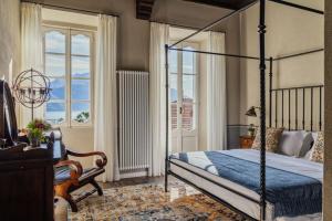 a bedroom with a bed and a chair and windows at Villa Issima "The Menaggio Suite" - Menaggio by LoveComo in Menaggio