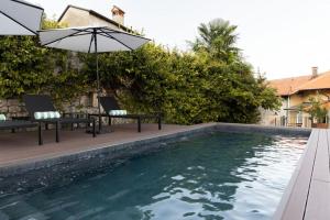 a swimming pool with two chairs and an umbrella at Villa Issima "The Menaggio Suite" - Menaggio by LoveComo in Menaggio