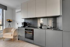 een keuken met witte kasten, een wastafel en een stoel bij Scala City Center Apartments with Parking by Lion Apartments in Gdańsk