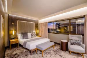 a bedroom with a bed and a chair and a window at Sandton Sun and Towers in Johannesburg