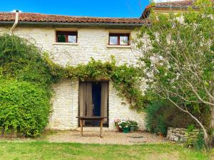 una casa di mattoni con una panchina davanti di Le Noisetier at Les Hiboux Gites a Chef-Boutonne