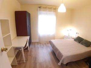 ムルシアにあるAPARTAMENTO TORRETAのベッドと机と窓のある寝室
