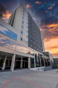 布卢梅瑙Hotel Caiuá Blumenau的一座白色的大建筑,背面有日落