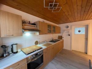 a kitchen with wooden cabinets and a stove top oven at Ferienwohnungen Goldhahn in Eibenstock