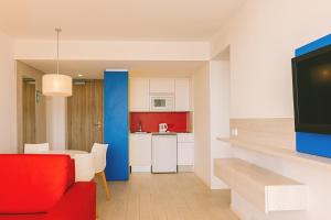 a living room with a red couch and a kitchen at Aparthotel Novo Mar in Paguera