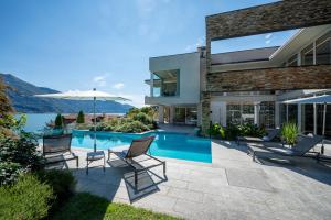 a house with a swimming pool with chairs and an umbrella at Villa Koi - where luxury meets serenity in Pianello Del Lario