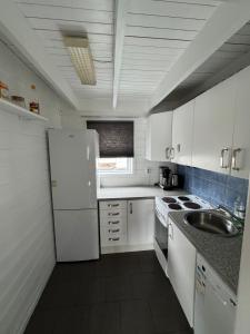 eine weiße Küche mit Spüle und Kühlschrank in der Unterkunft Cozy Oceanfront Escape in Nautnes + 9 Fotos