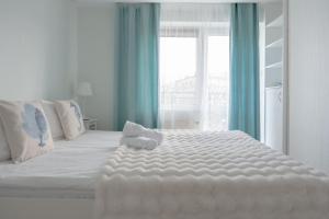a white bed with a teddy bear sitting on top of it at Apartamenty in Blue Wave in Jastarnia
