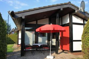 a red umbrella and some chairs and a table at Ferienhaus Schöps in Burhave