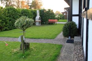 a garden with a bench and a tree in the grass at Ferienhaus Schöps in Burhave +3 photos