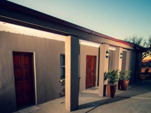 a building with two doors and two potted plants at Donsveertjie Gasteplaas & Venue in Heilbron +6 photos