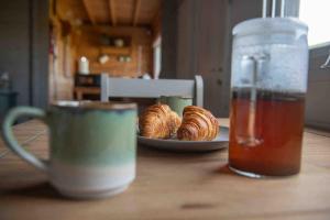 a table with a cup of tea and a plate of croissants at Cwt Gafr Bach in Pwllheli +13 photos