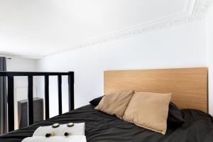 Bett mit einem Kopfteil aus Holz und 2 Kissen in der Unterkunft GuestReady - Snug spot near Parc Paumier in Meudon