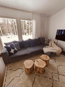 un soggiorno con divano e 2 sgabelli in legno di Arctic Hideout a Rovaniemi