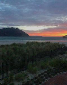 a sunset over a body of water with a fence at Beachfront @ Beach Club in Cape Town +51 photos