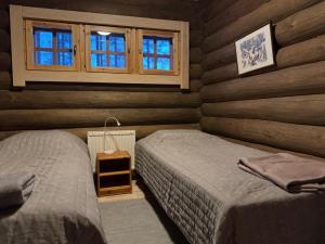 two beds in a room with wooden walls and windows at Soutajanhattu in Pyhätunturi