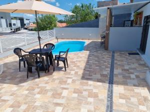 un patio avec une table, des chaises et un parasol dans l'établissement Espaço Aconchegante no Centro da Cidade, à Águas de São Pedro