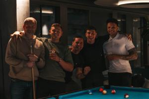 a group of men standing next to a pool table at Next House Copenhagen in Copenhagen