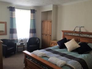 a bedroom with a bed and two chairs and a window at Maon Hotel in Brighton & Hove