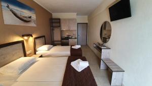 a hotel room with two beds and a television at Calypso Beach Hotel in Paralia Katerinis +65 photos