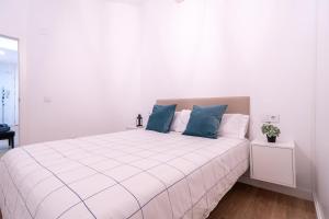 Un dormitorio con una cama blanca con almohadas azules. en Apartamento en el casco antiguo de Murcia, en Murcia