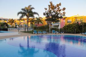a large swimming pool with blue chairs and buildings at Apartamentos da Orada T1-F124 Marina de Albufeira in Páteo