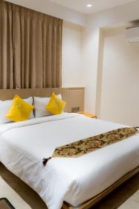 een slaapkamer met een groot wit bed met gele kussens bij Rainbow Guest House - Pure Veg in Guwahati +52 foto's