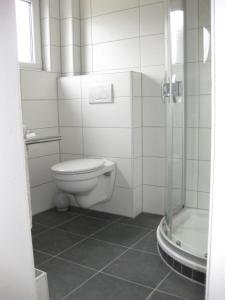 a white bathroom with a toilet and a shower at Ferienhaus Sylvia in Hoddersdeich
