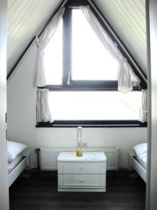 a room with a window with two beds and a table at Ferienhaus Sylvia in Hoddersdeich