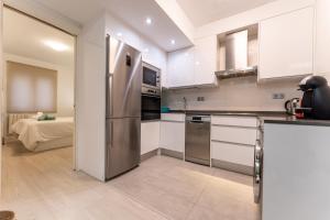 a kitchen with a stainless steel refrigerator and white cabinets at el rincon de tetuan in Santander