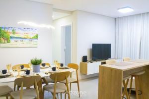 a dining room with a table and chairs and a tv at Modern apartment with barbecue CRR201 in Florianópolis