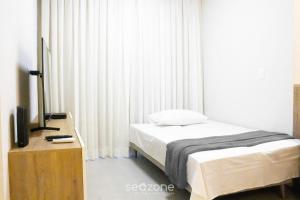 a bedroom with a bed and a tv and curtains at Modern apartment with barbecue CRR201 in Florianópolis