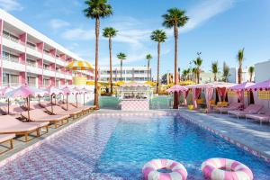 a swimming pool with chairs and umbrellas and palm trees at Los Felices Ibiza in San Antonio Bay