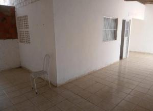 a chair sitting in a room with a white wall at Casa para alugar temporária in Maceió