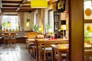 a restaurant with wooden tables and chairs and windows at Hotel Up de Birke in Ladbergen