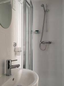 baño blanco con ducha y lavamanos en Maon Hotel, en Brighton & Hove