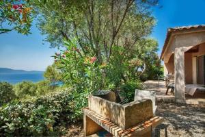 una panchina in un giardino con vista sull'acqua di Charmante maison à Olmeto avec piscine partagée a Olmeto