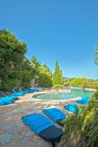 una piscina con sedie a sdraio blu in un resort di Charmante maison à Olmeto avec piscine partagée a Olmeto