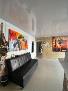 a black leather couch in a room with paintings at NaPoles valledupar Hotel in Valledupar