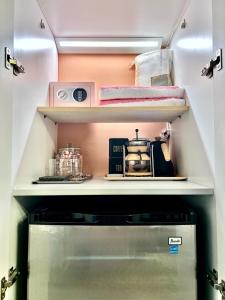 a small kitchen with a shelf above a refrigerator at Double Rainbow Suites 24th in Fort Lauderdale