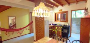 a kitchen with a dining table and a chandelier at Casa Dos Ventos Hospedagem Praia do Rosa in Praia do Rosa
