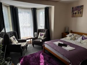 a bedroom with a bed and two chairs and windows at Willows Guest House in Great Yarmouth