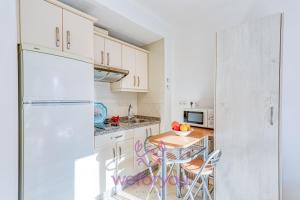 a kitchen with white cabinets and a table and chairs at weforyou Old Town Benalmadena in Benalmádena