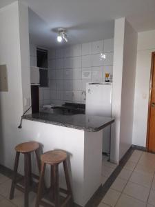 a kitchen with two stools and a counter with a refrigerator at Rio Quente Thermas Paradise in Rio Quente