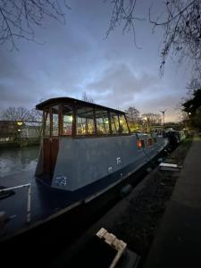 a small boat sitting on the side of a river at London Dutch Barge - Sleeps 3 & Cosy Fireplace in London