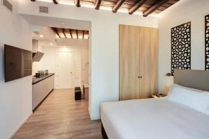 a bedroom with a white bed and a kitchen at Sercotel Granada Suites in Granada